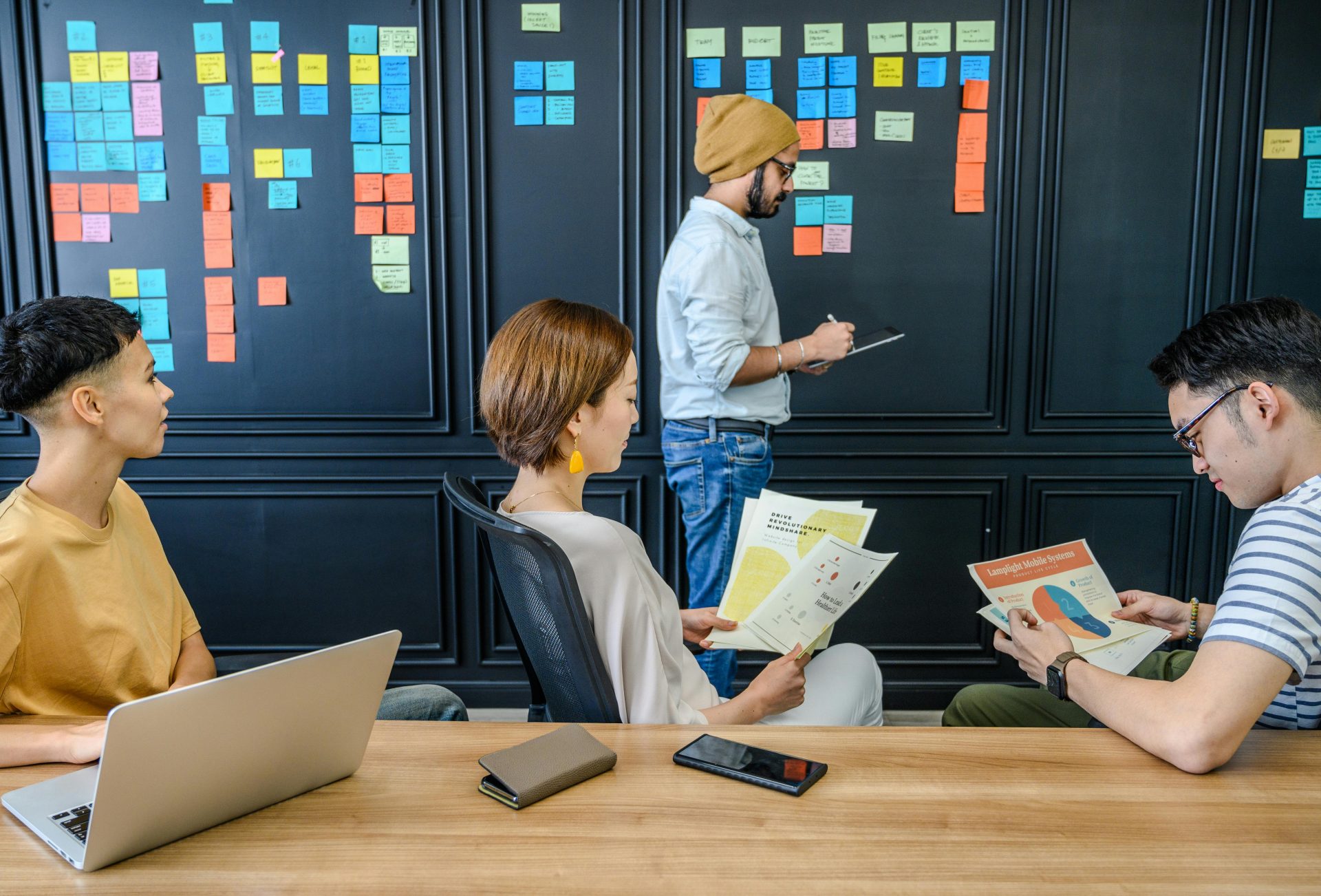 Group of colleagues engaged in a brainstorming session with sticky notes and documents in a modern office setting.