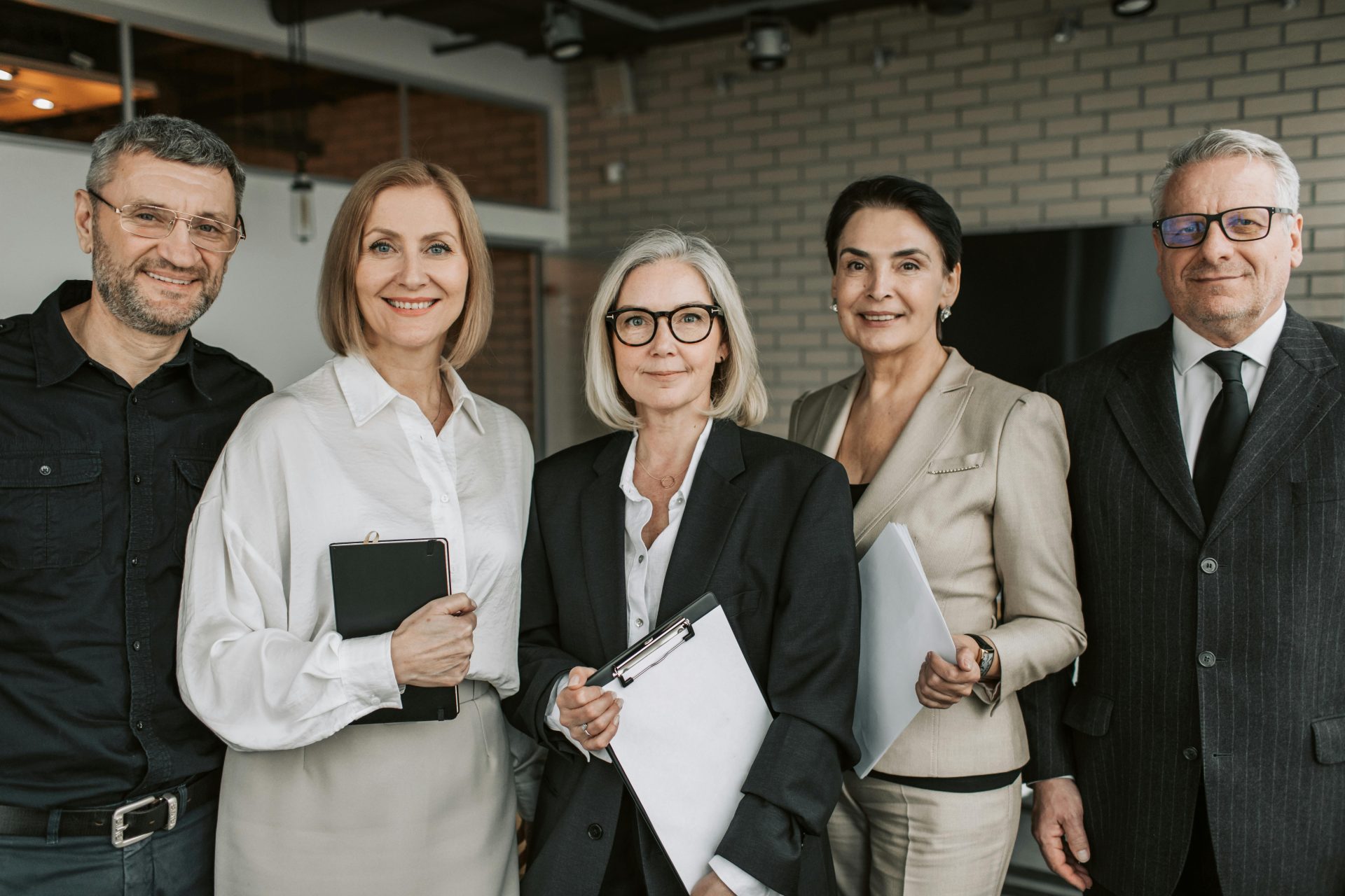 A diverse team of senior business professionals posing confidently indoors.